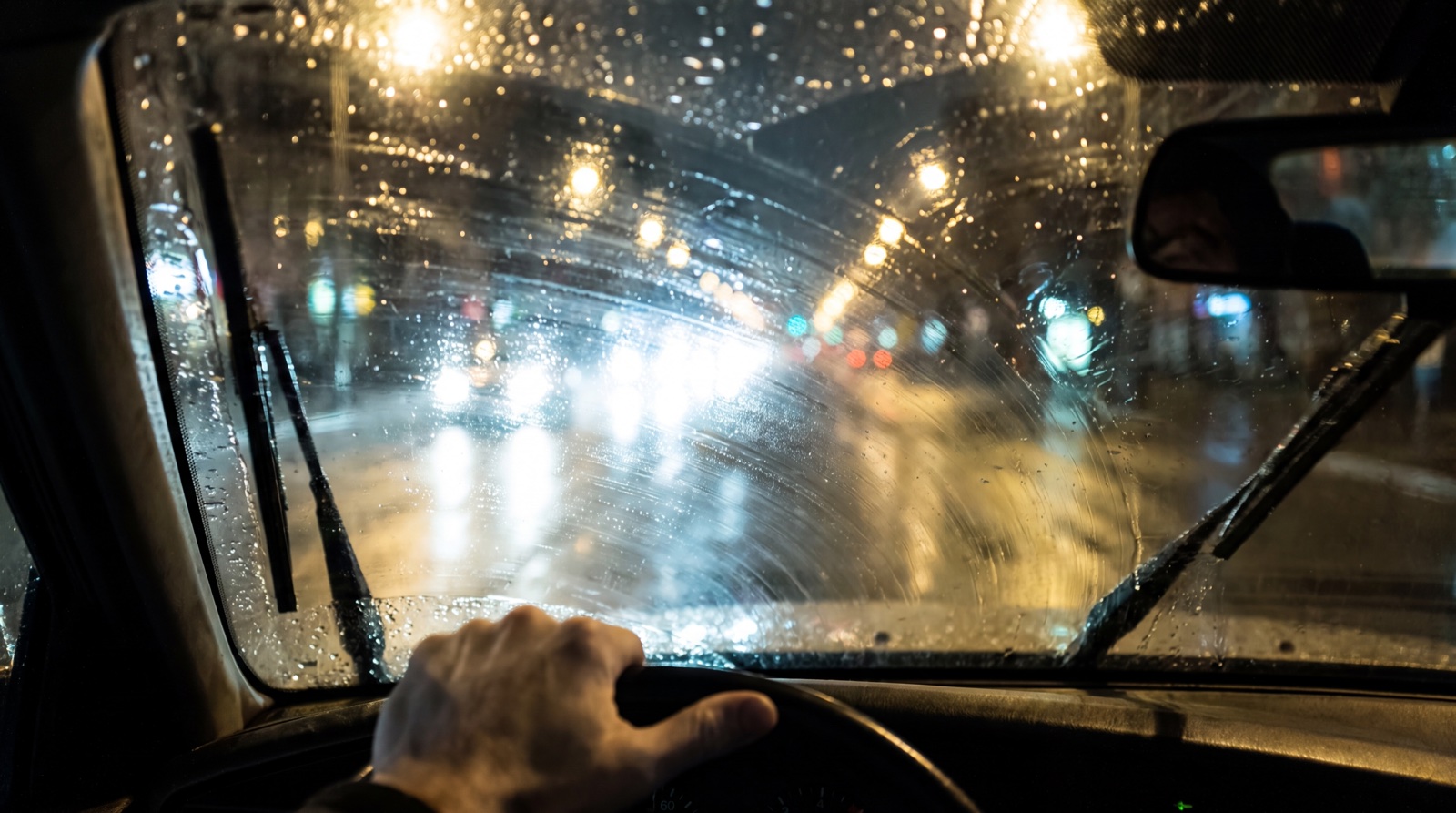 雨夜駕駛透過油膜霧化的擋風玻璃,對向車燈眩光刺眼、視線模糊
